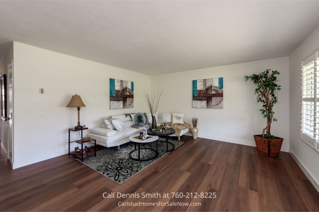 Spacious living room at 4414 Chickadee Way Oceanside Home for Sale with hardwood floors, white sectional sofa, modern decor, and abundant natural light.