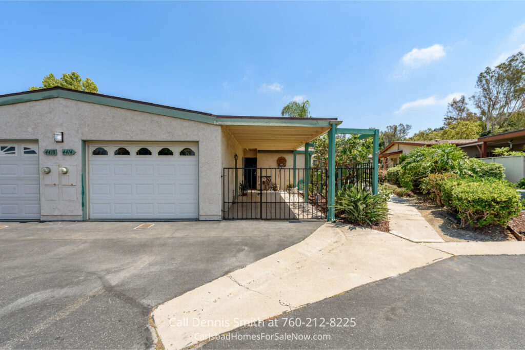 Attached garage of 4414 Chickadee Way Oceanside Home for Sale with gated patio, driveway, and landscaped walkway