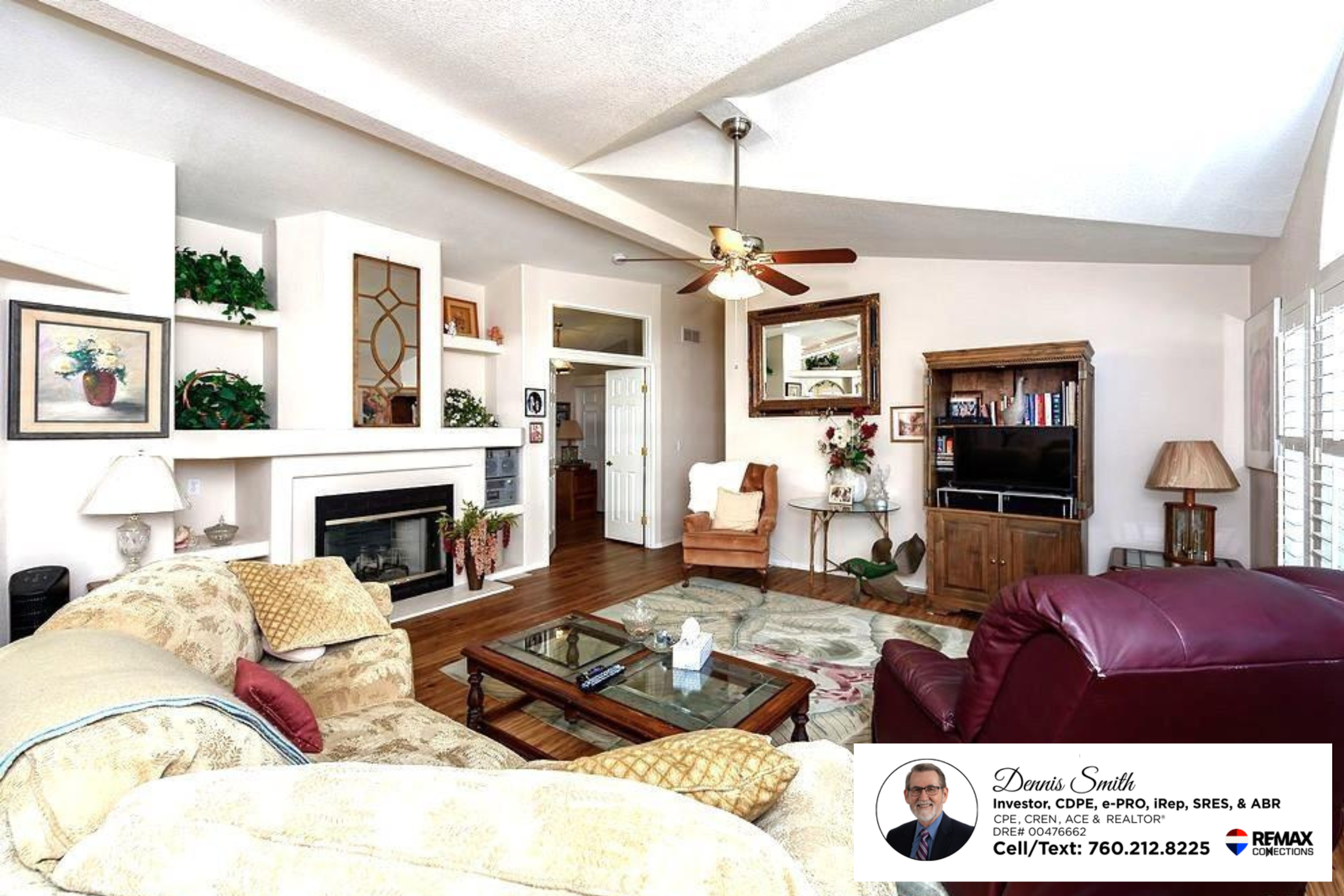 Bright and inviting living room with vaulted ceilings, skylights, wood style flooring, a fireplace, ceiling fan, and comfortable seating arranged in an open concept layout filled with natural light.