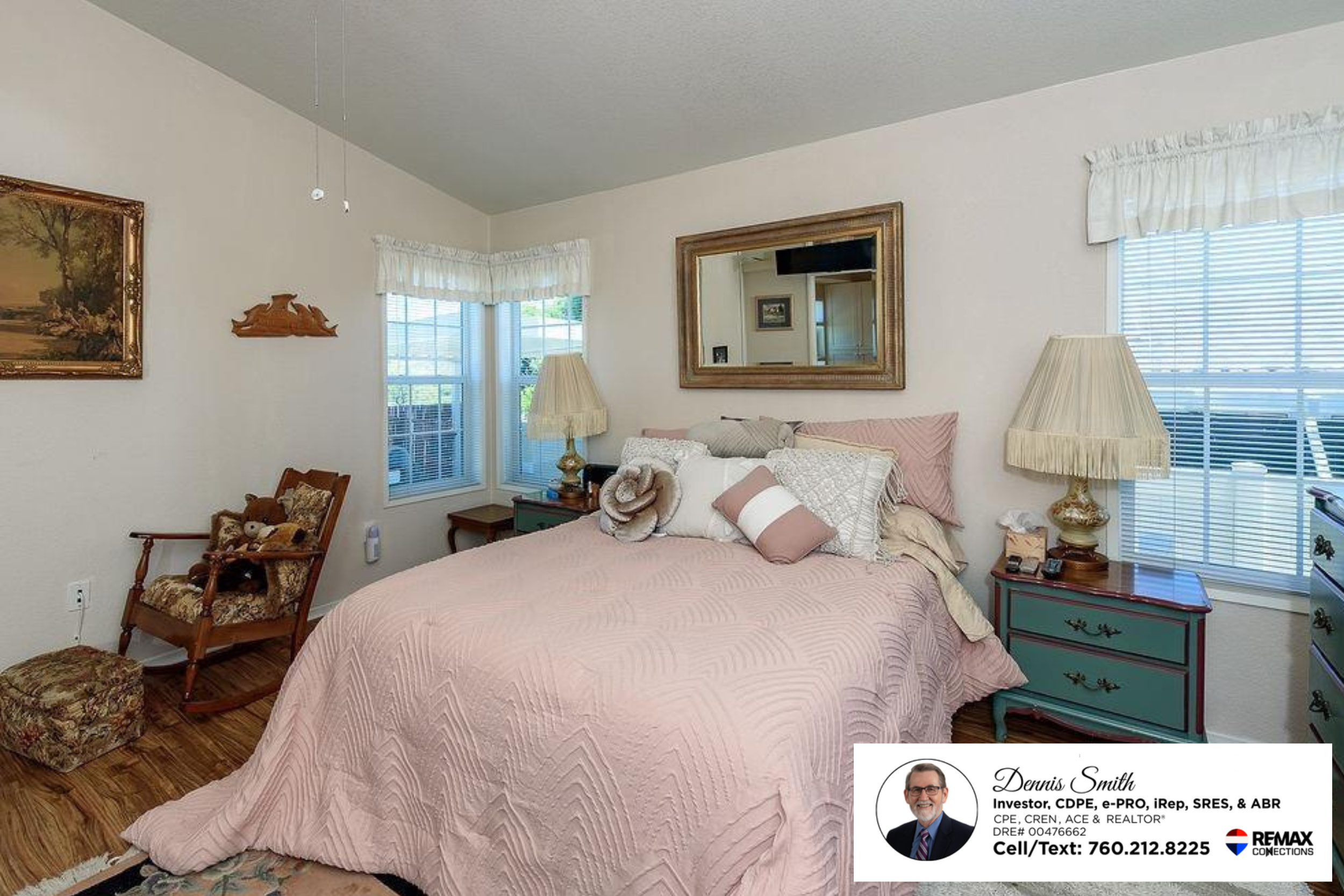 Cozy primary bedroom with soft neutral walls, large corner windows, wood flooring, bedside tables, decorative accents, and natural sunlight creating a peaceful and relaxing retreat atmosphere.