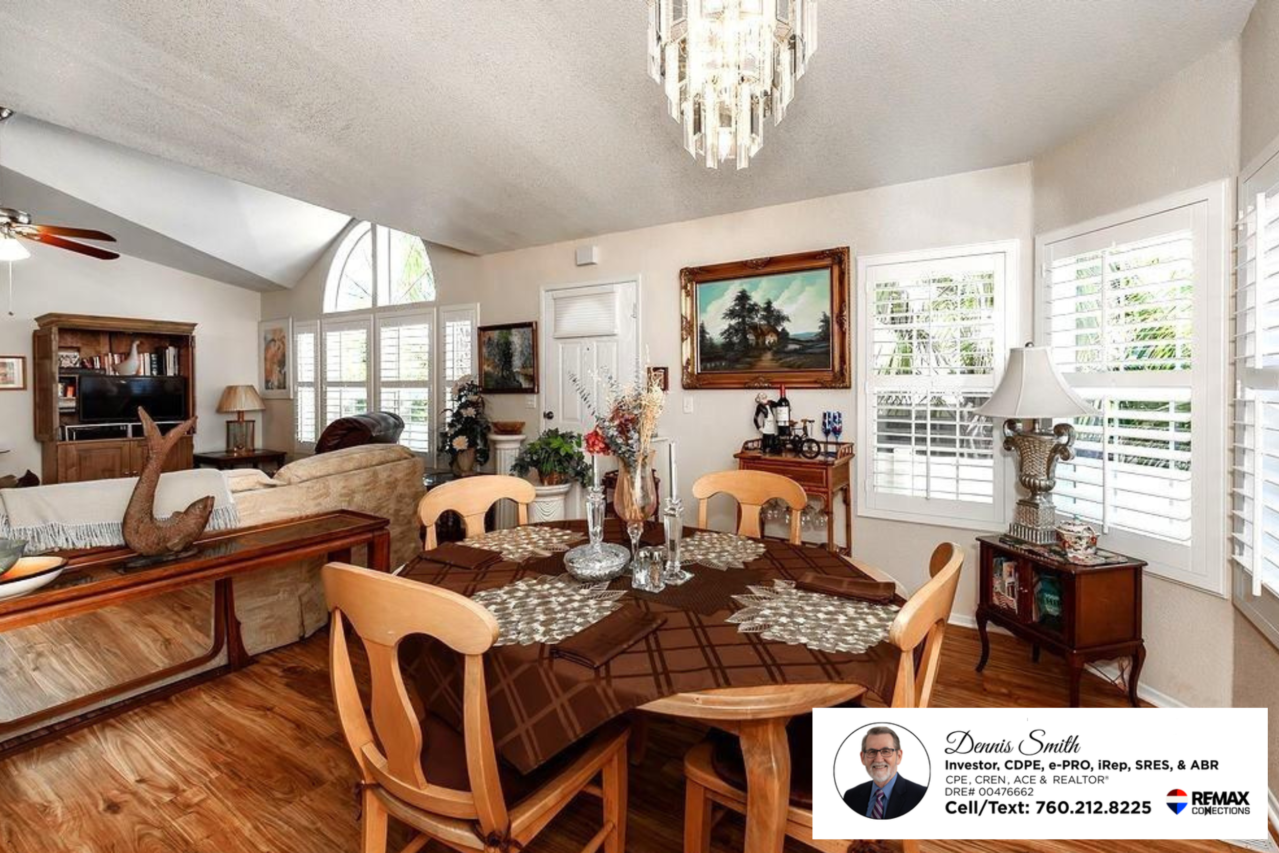 Elegant dining room with wood flooring, vaulted ceilings, large windows with plantation shutters, decorative chandelier lighting, and an open layout connected to the spacious living area.