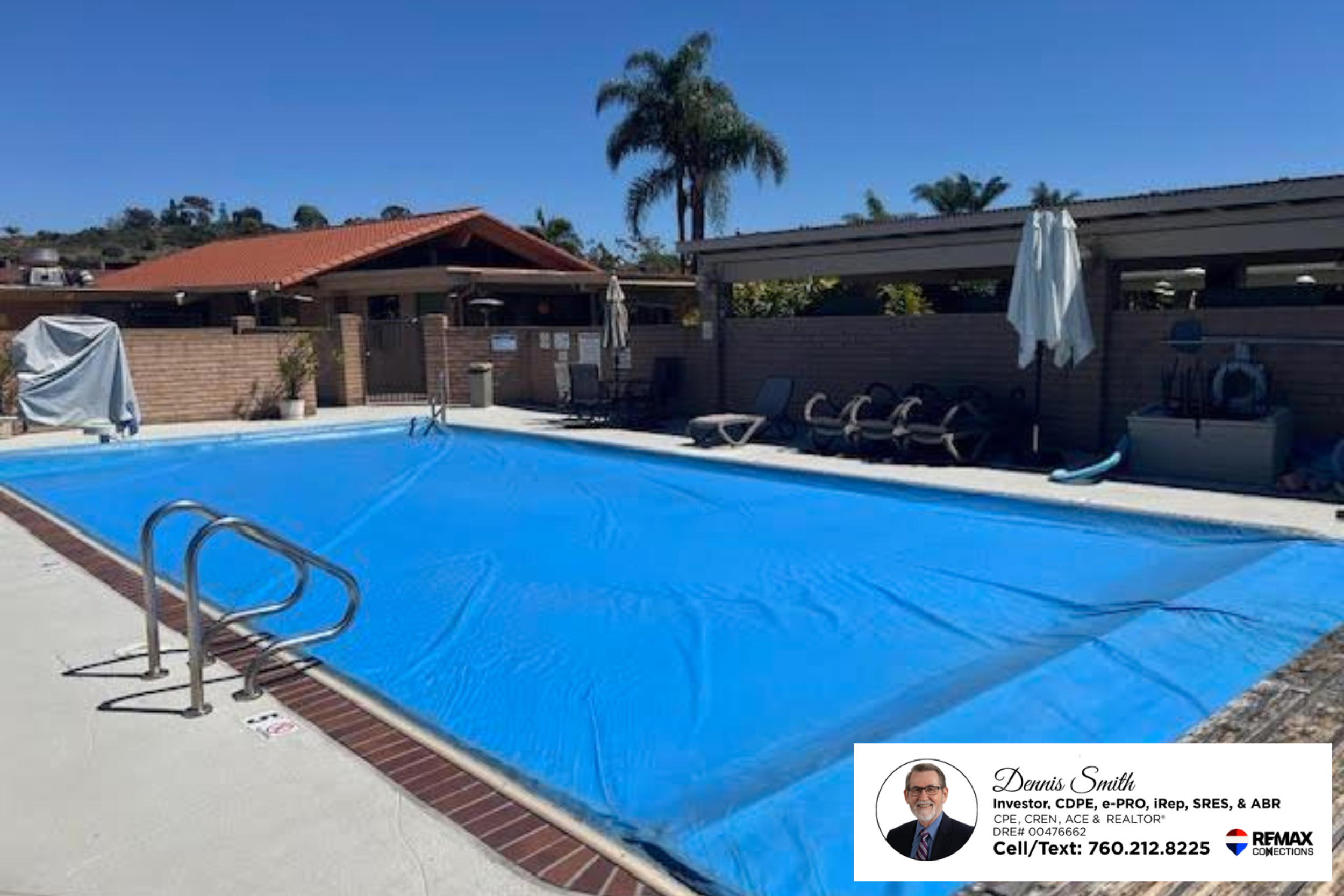 Resort style community swimming pool with lounge seating, shaded patio areas, palm trees, and sunny blue skies located within a peaceful and active adult community in Encinitas California.